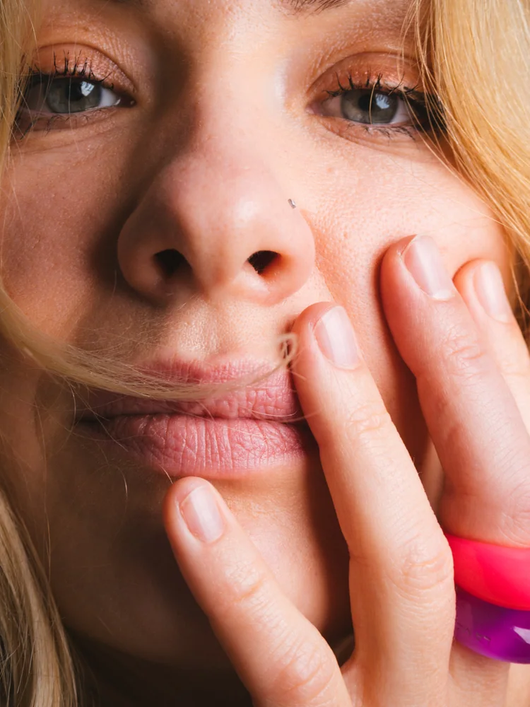 Close-up portrait of a smiling woman resting her face in her hands