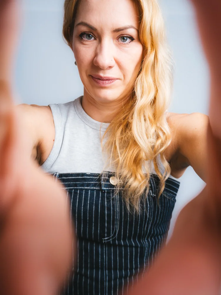 Studio portrait of a woman reaching toward the camera against a pale blue background