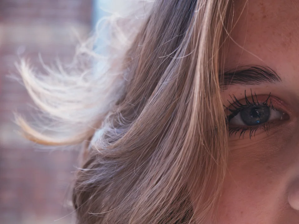 Detail portrait of a woman's eye framed by windswept hair