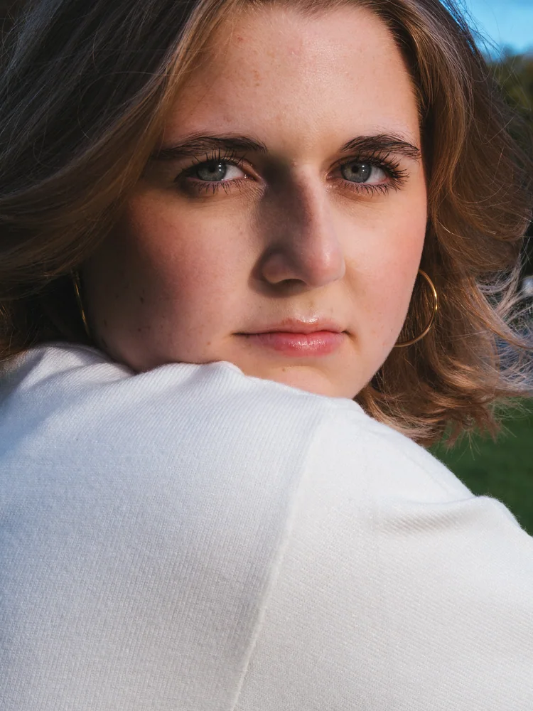 Close-up portrait of a woman looking over her shoulder in a white sweater