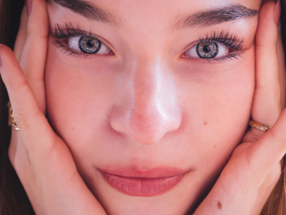 Close-up portrait of a woman framing her face with her hands