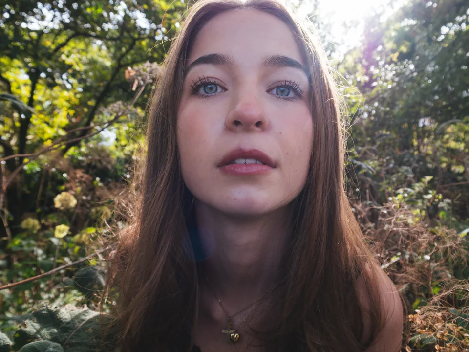 Outdoor close-up portrait of a woman beneath sunlit trees