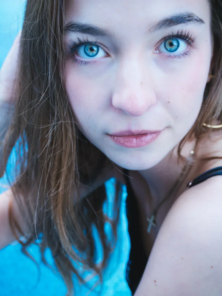 Close-up portrait of a woman with blue eyes against a blue background