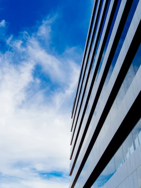 Parallel lines of a modern building against a blue, cloudy sky.
